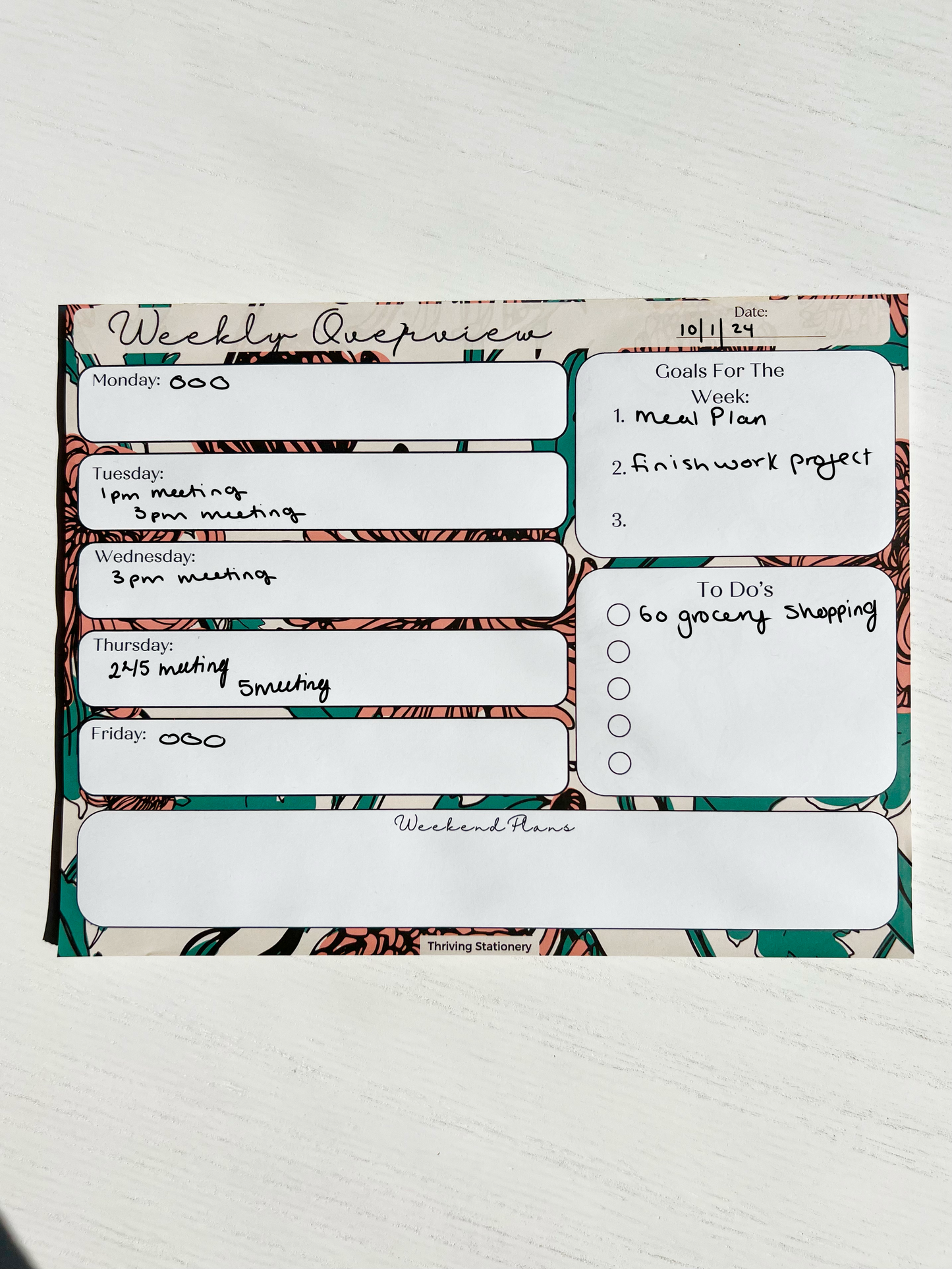 Weekly planner notepad with bold floral background featuring daily sections, weekly goals, to-do list with checkboxes, and weekend planning space.