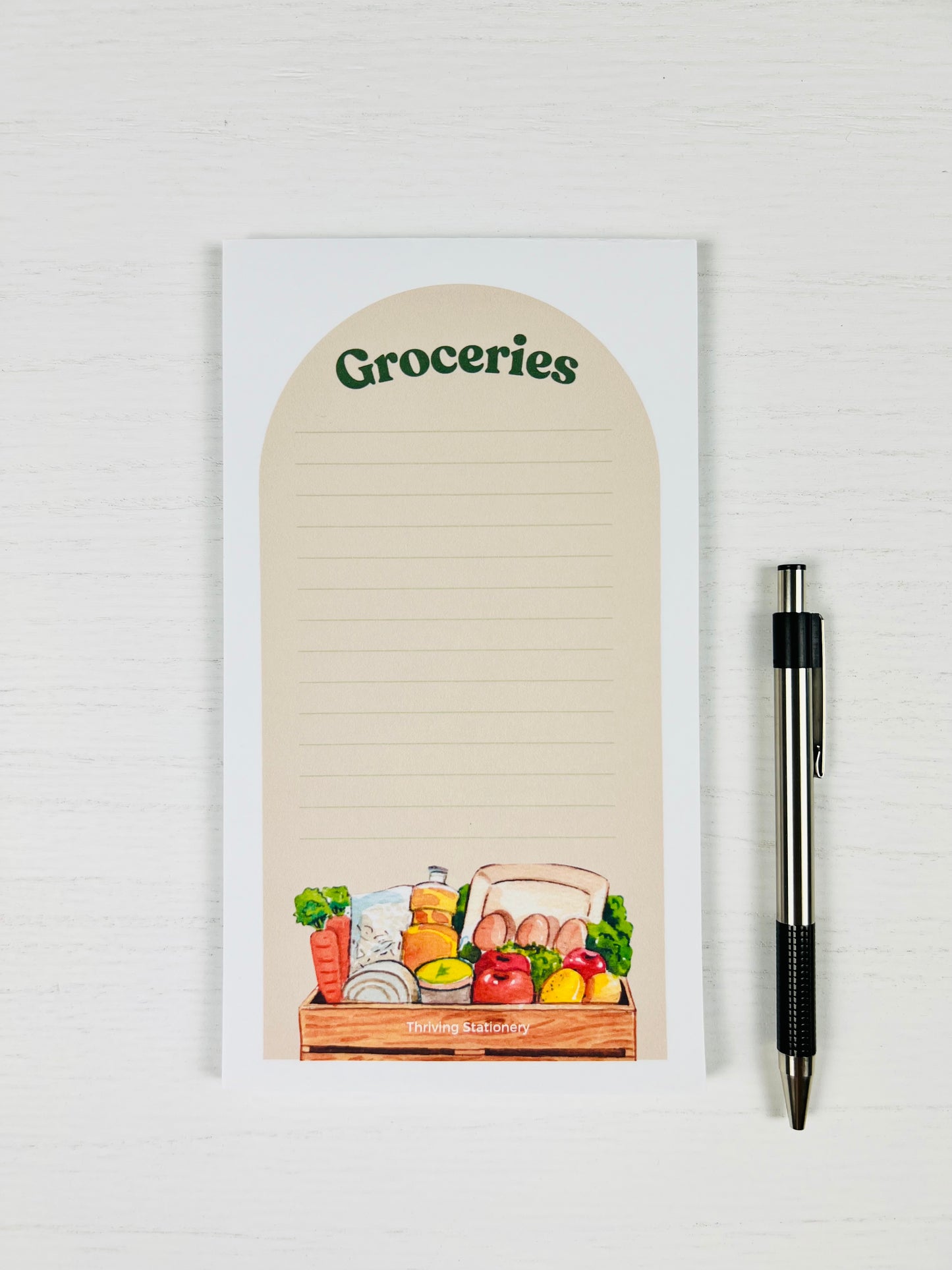 Farmstand Magnetic Grocery List Notepad with illustrated fruits and vegetables and lined layout with a pen for scale