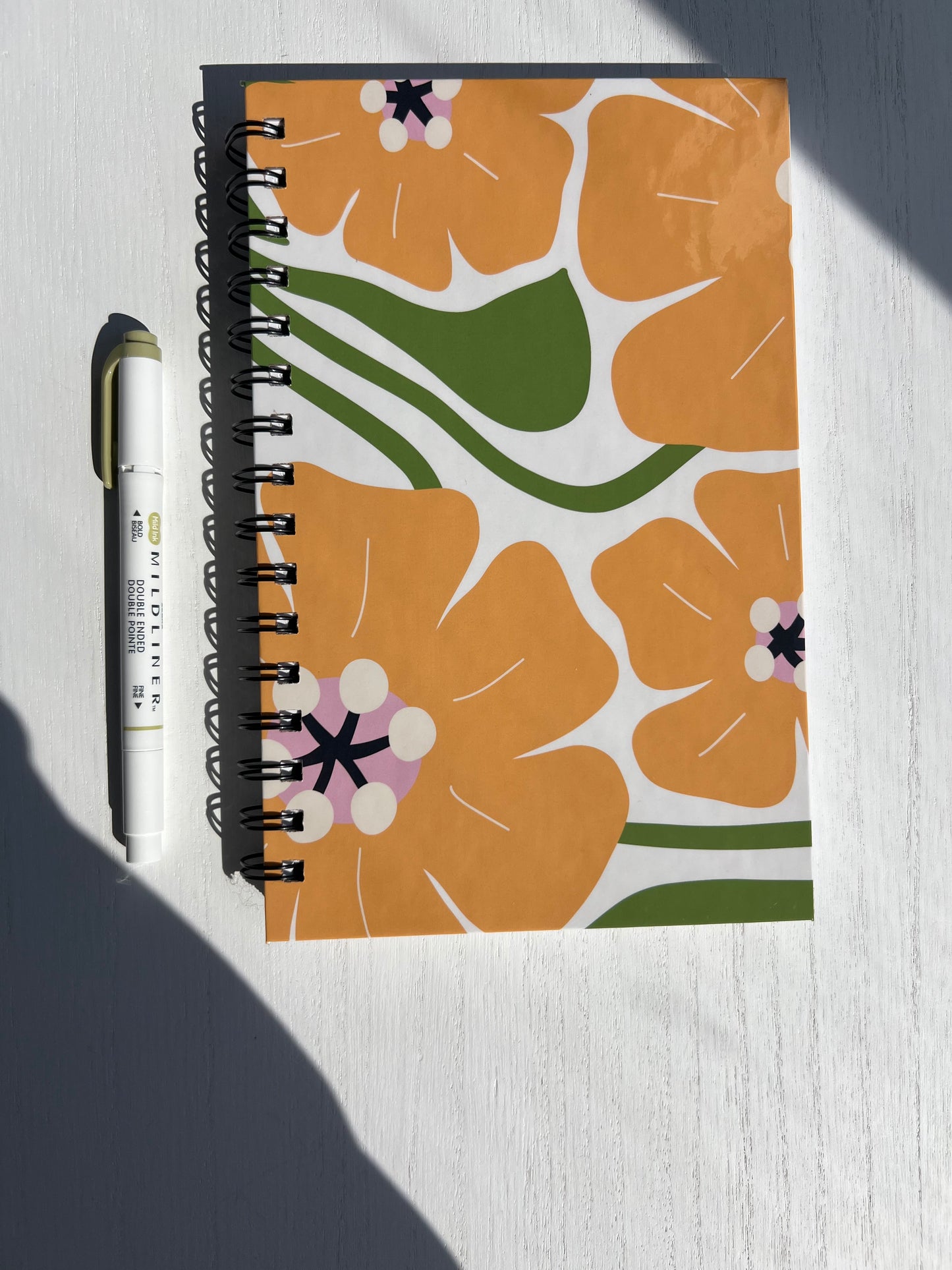 Spiral notebook featuring a bold retro orange and green floral cover with 115 double-sided lined pages from Thriving Stationery.