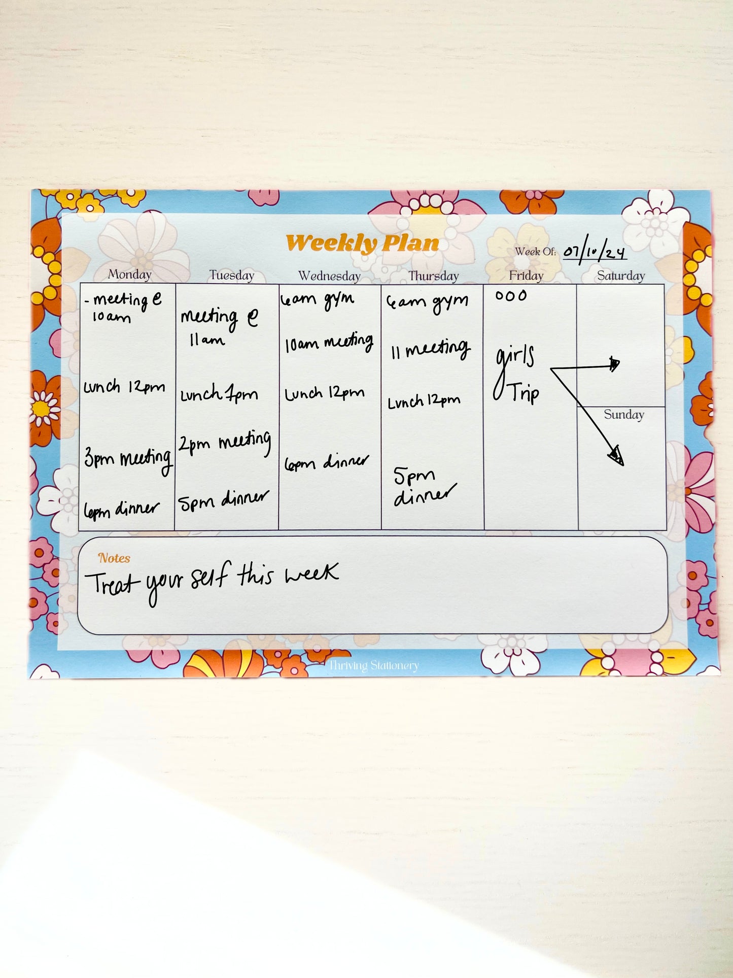 Colorful floral-themed weekly planner notepad with 7 columns for each day of the week and a large notes section at the bottom.