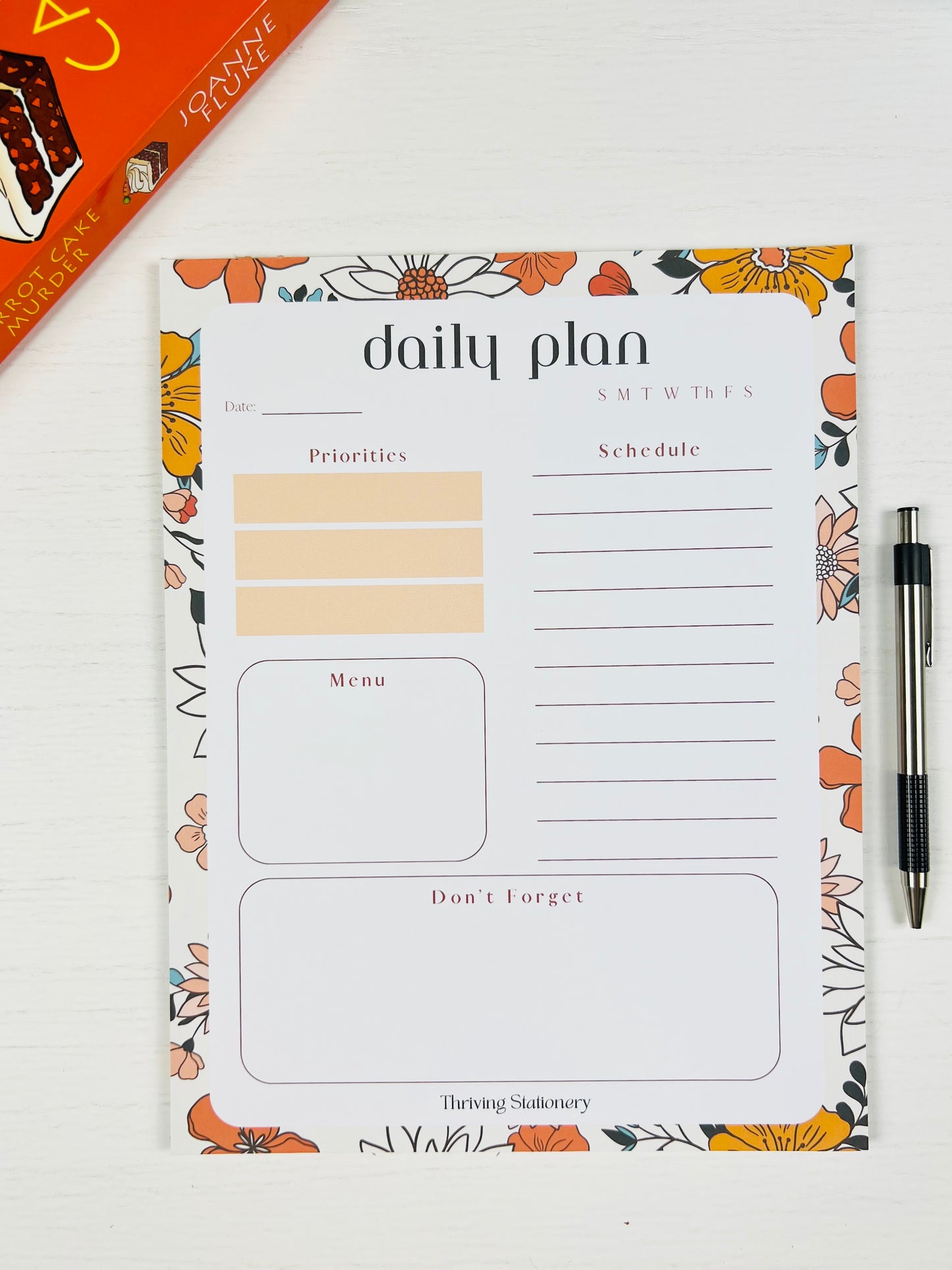 Vibrant Floral Daily Planner Notepad with colorful floral design and a pen on white background