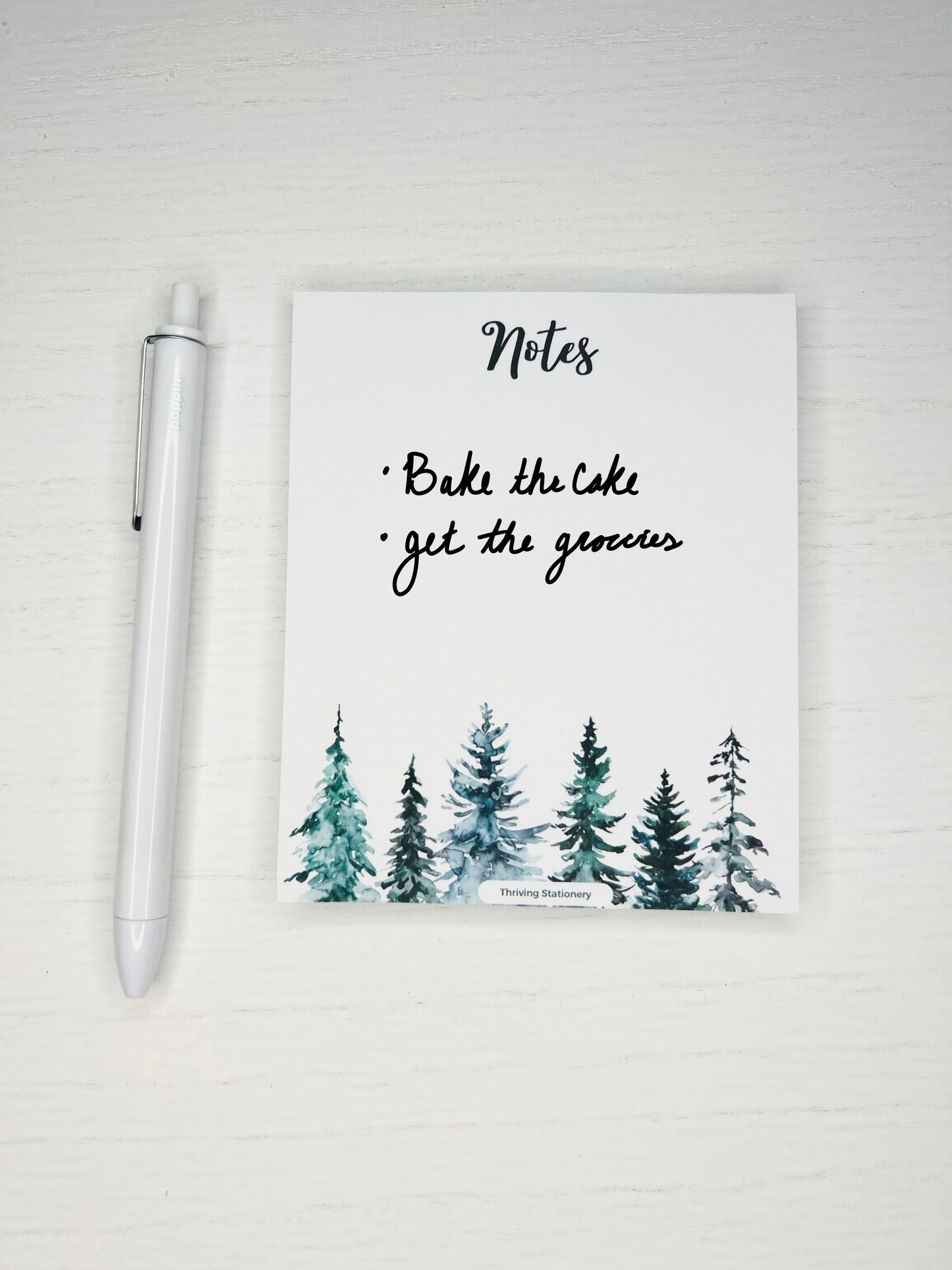 notepad with "Notes" in script at the top and watercolor pine trees across the bottom border.