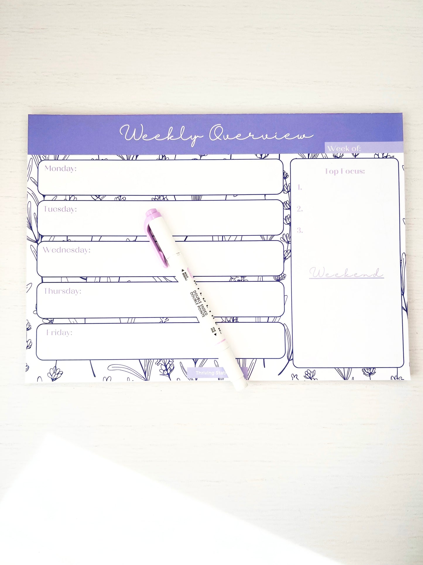 Lavender floral weekly planner notepad featuring daily sections, top 3 priority list, and weekend space on a white background.