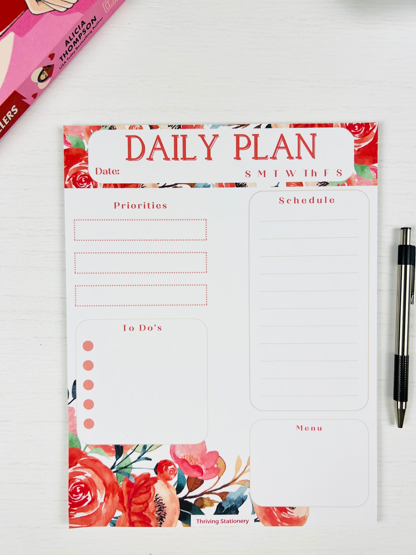 Daily plan notepad with floral design on a white surface