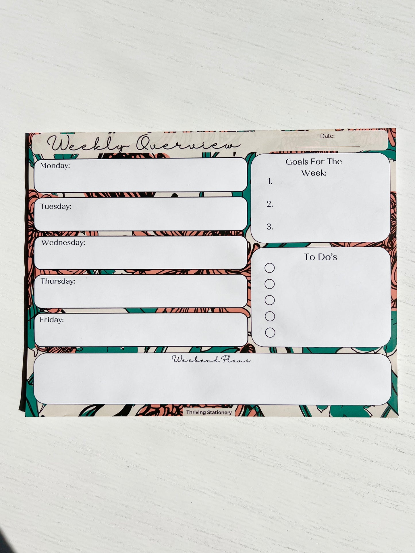Weekly planner notepad with bold floral background featuring daily sections, weekly goals, to-do list with checkboxes, and weekend planning space.