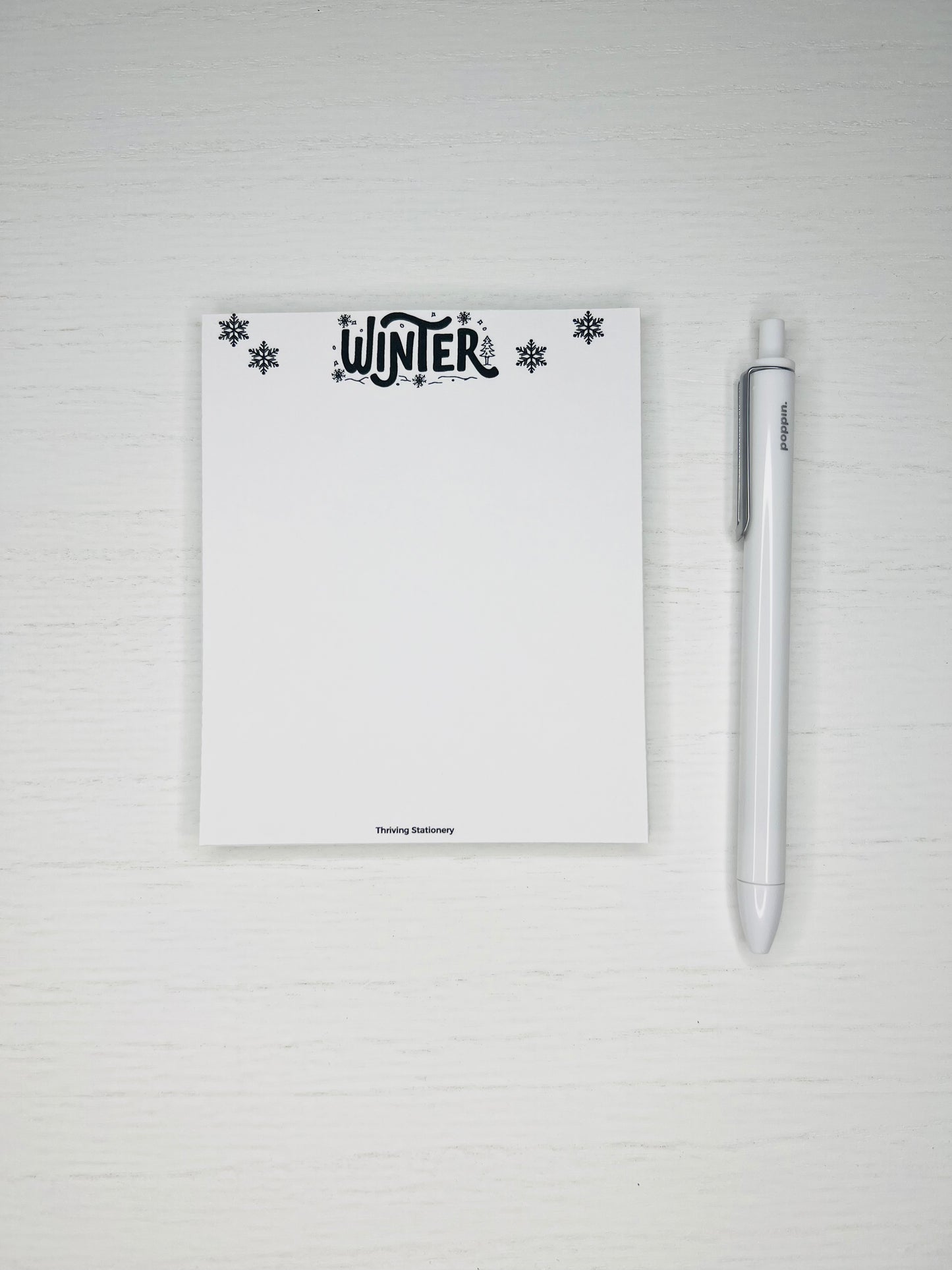 Minimal winter-themed notepad with black snowflakes and “Winter” lettering at the top, blank white writing space below.