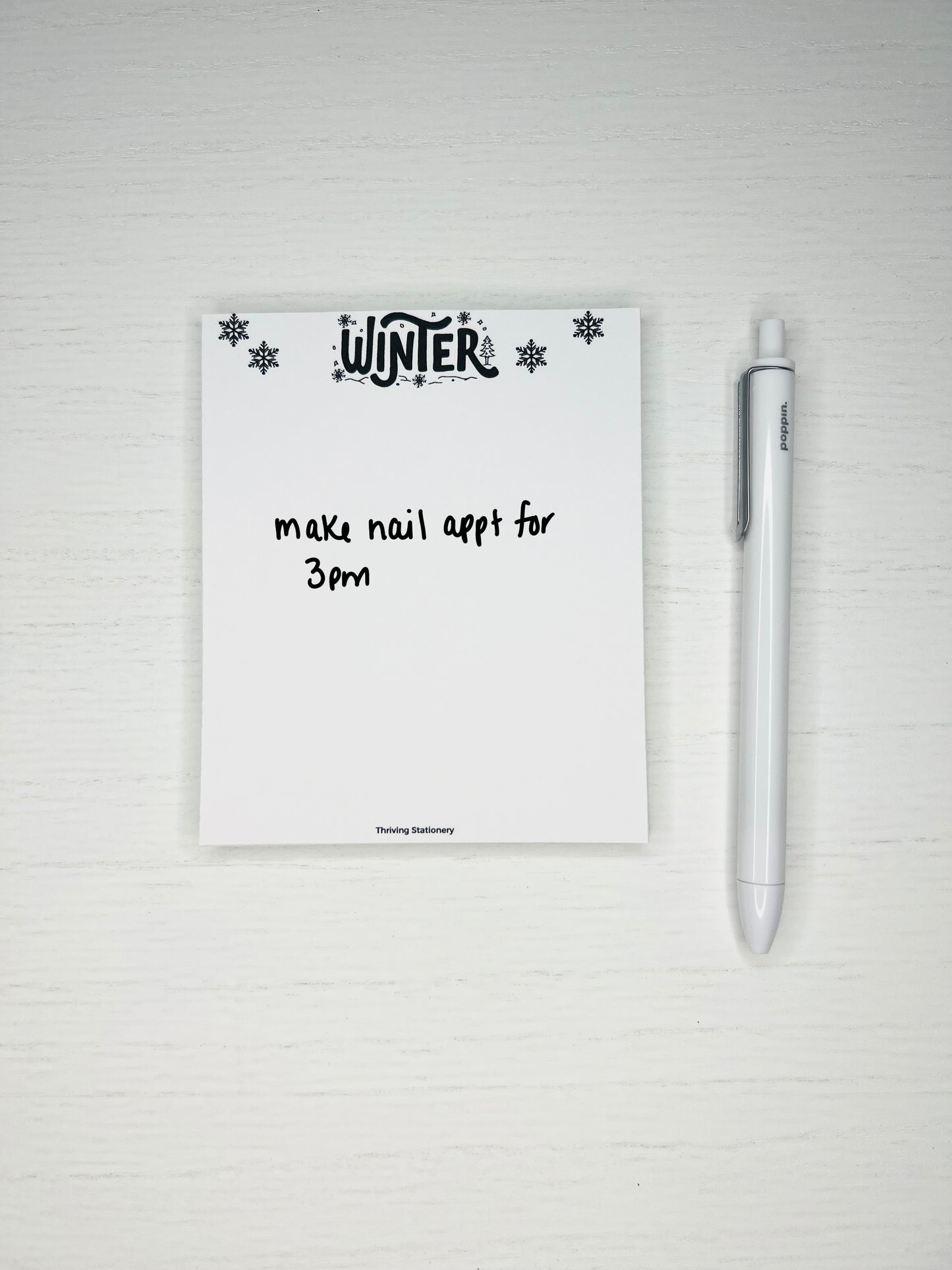Minimal winter-themed notepad with black snowflakes and “Winter” lettering at the top, blank white writing space below.
