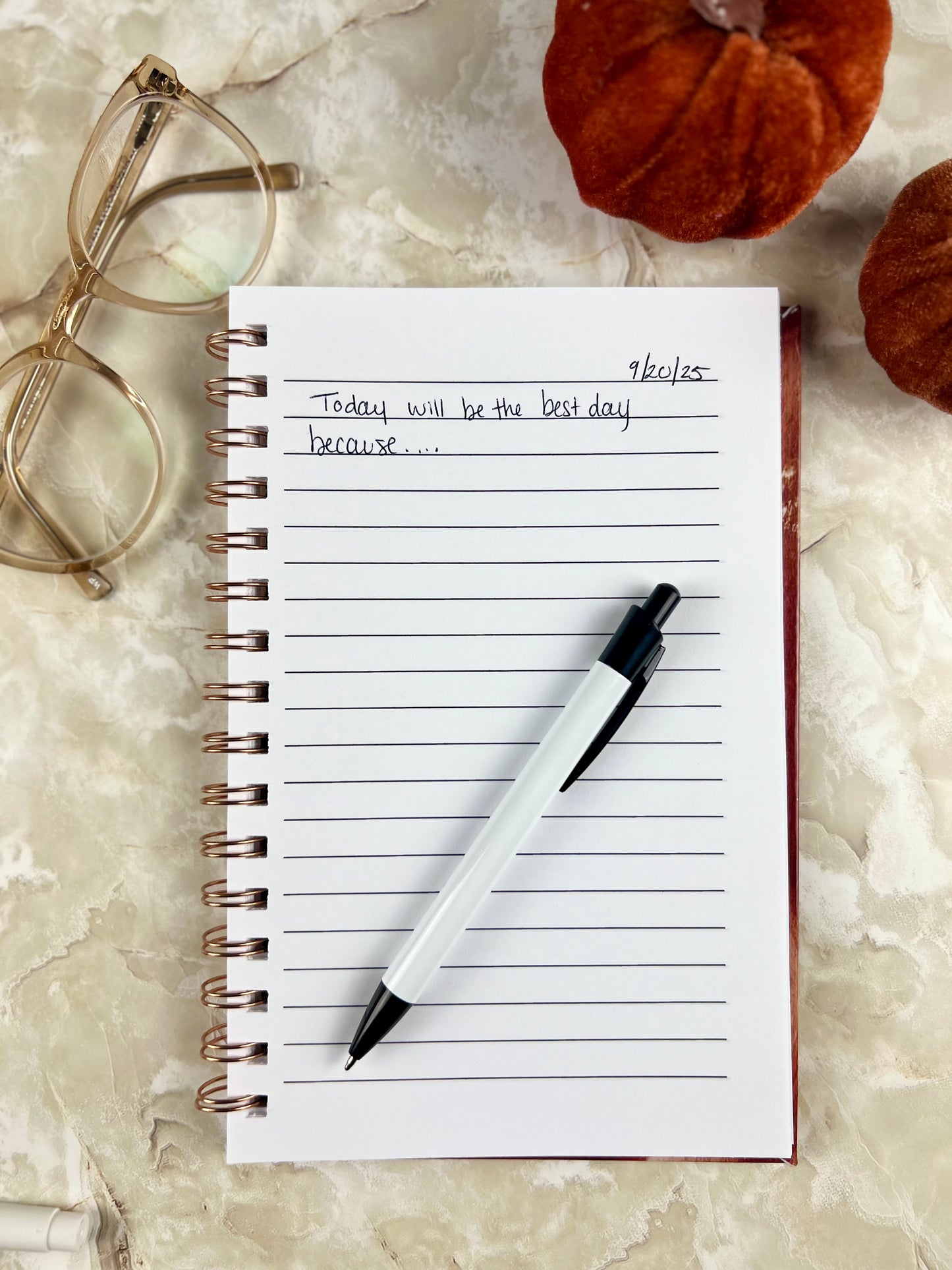 Notebook with pen and glasses on a marble surface