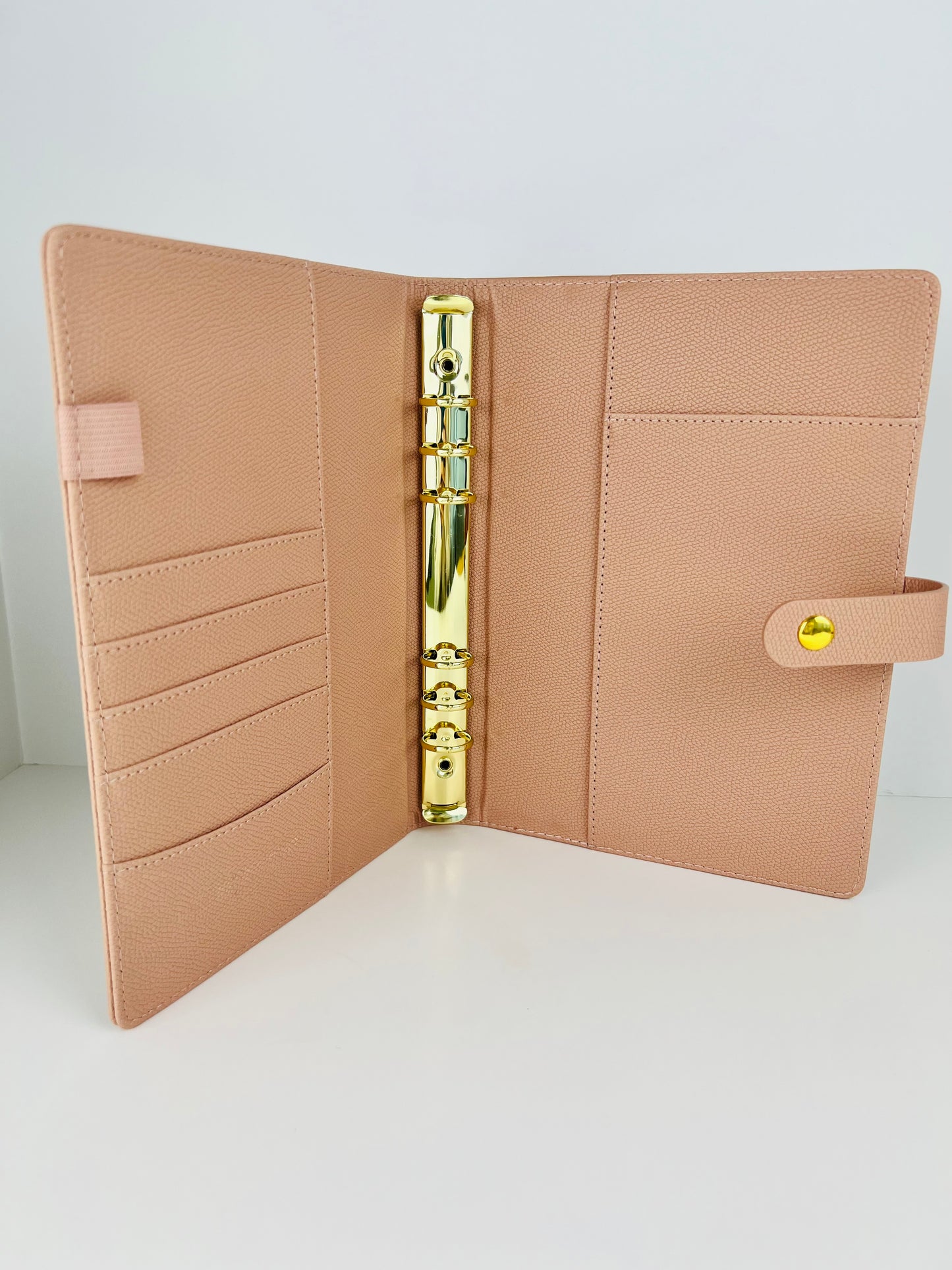 Beige planner cover with gold binding mechanism on a light gray background