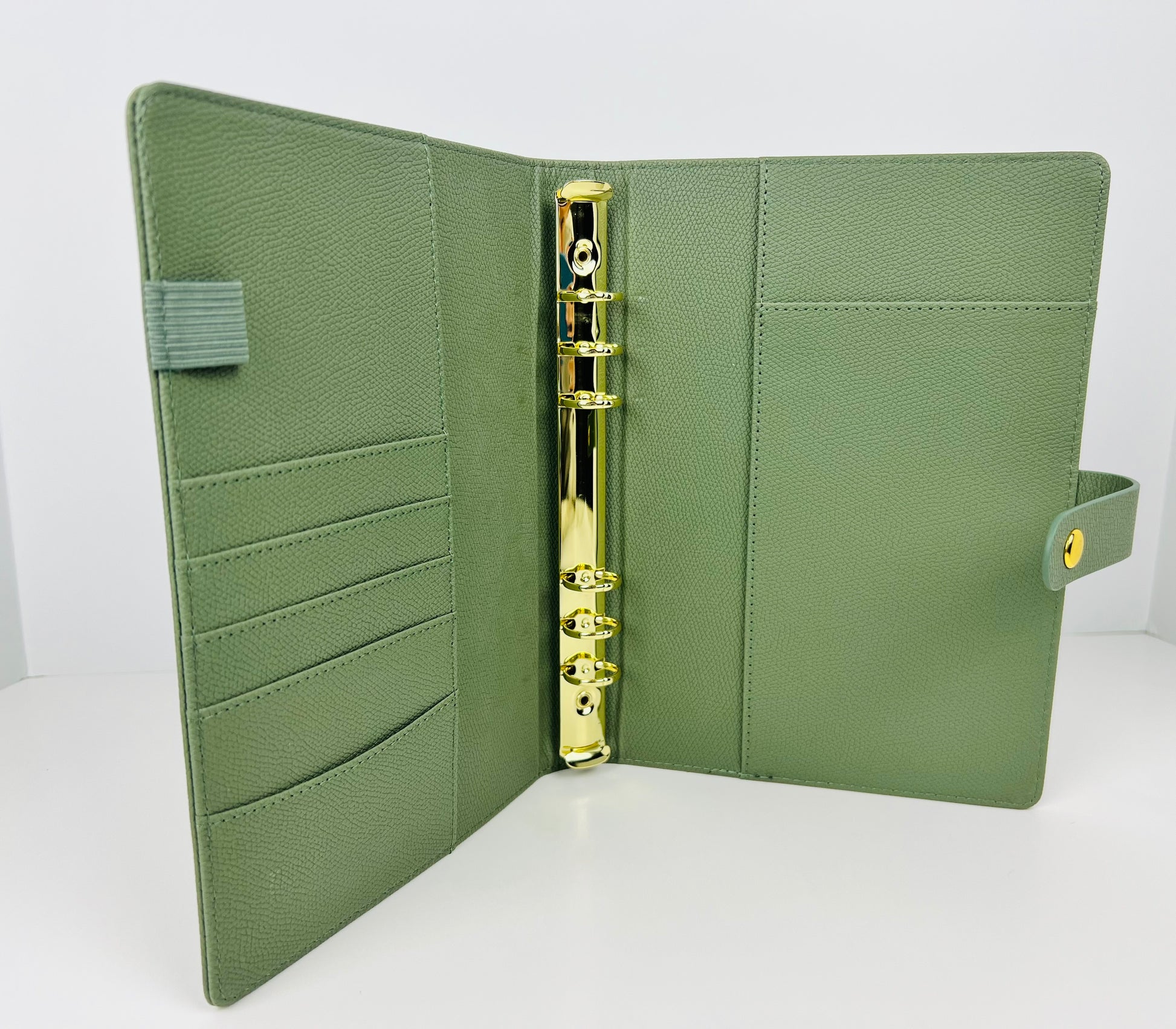 Green leather planner with gold ring binding on a white background
