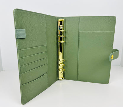 Green leather planner with gold ring binding on a white background