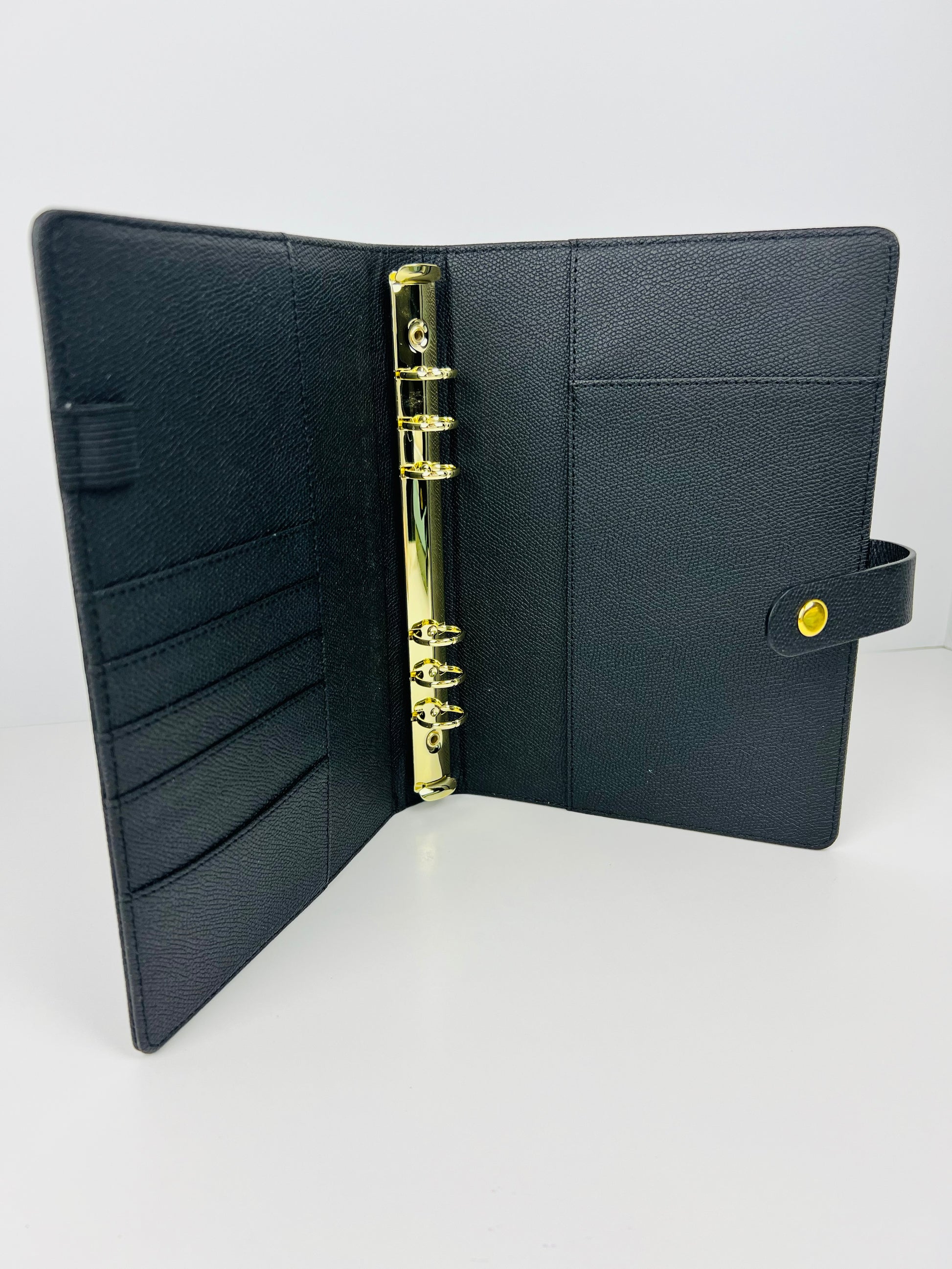 Black leather-bound notebook with gold binding on a white background