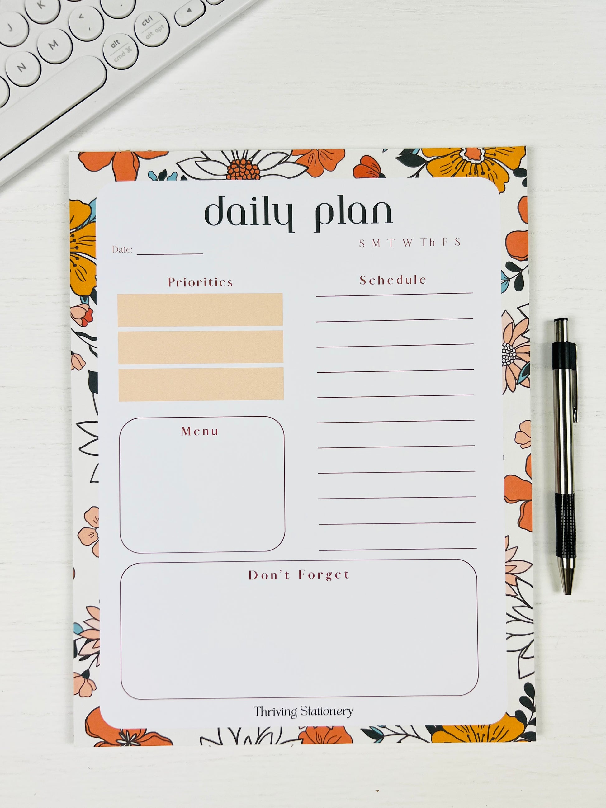 Vibrant Floral Daily Planner Notepad with colorful floral design with a pen and keyboard