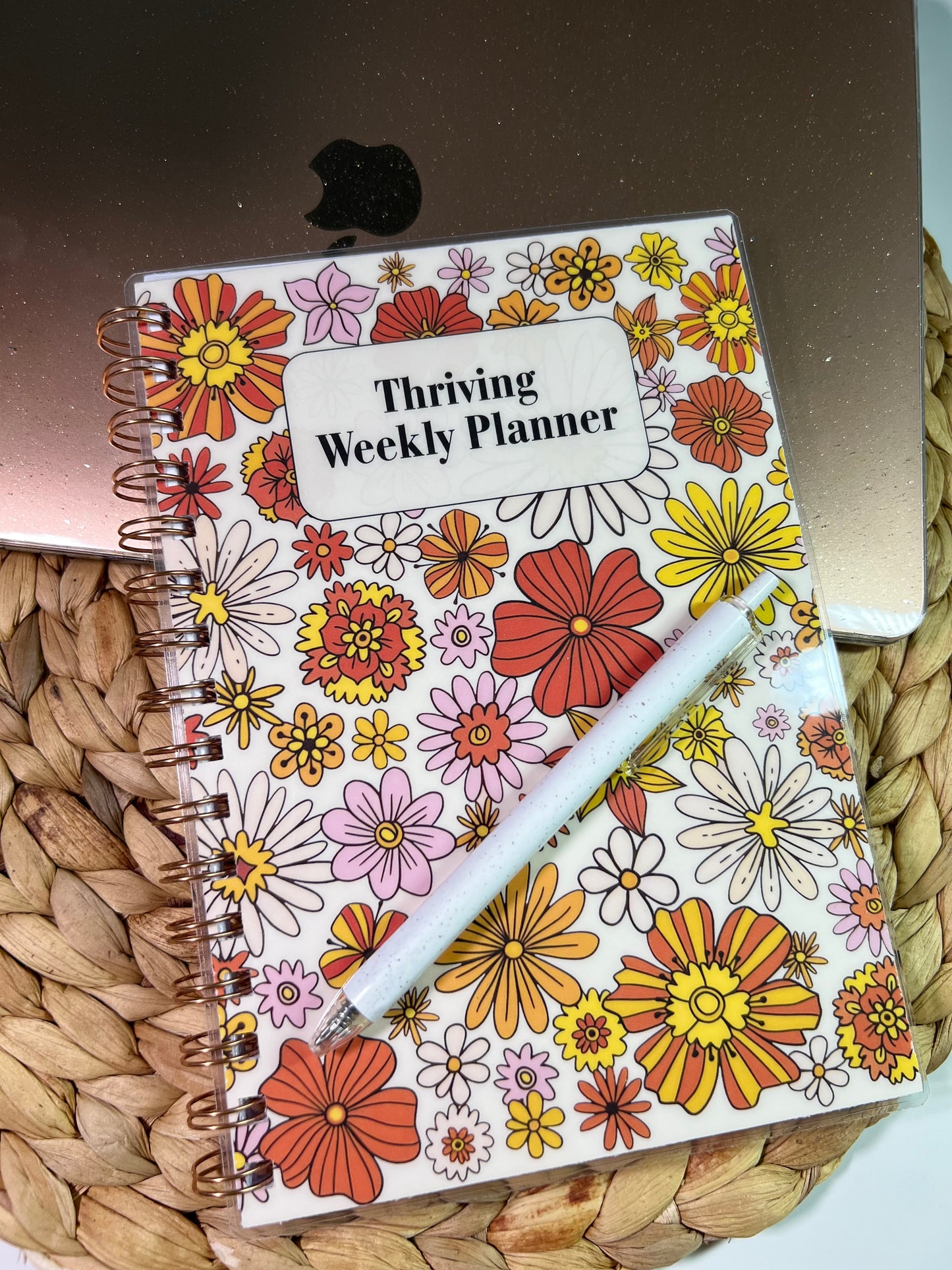 Floral planner with 'Thriving Weekly Planner' text on a woven surface