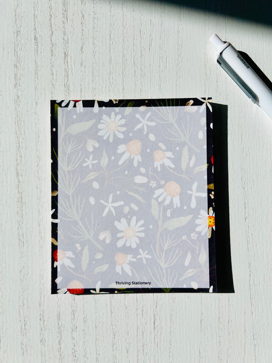 Whimsical floral notepad with daisy and greenery print in soft matte tones. “Thriving Stationery” printed at the bottom center.
