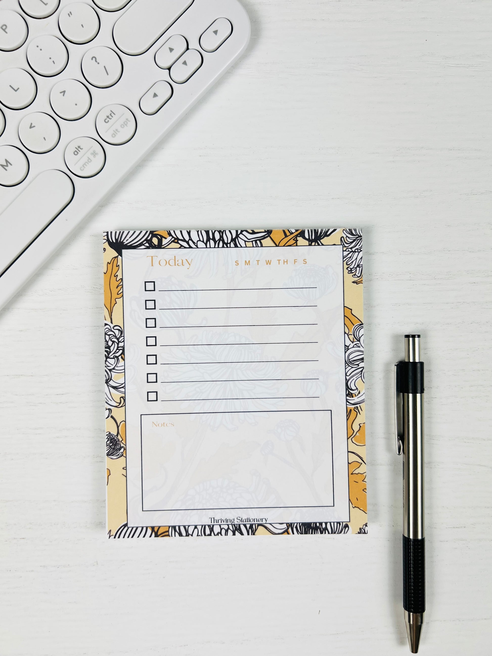 Black and Yellow Floral To-Do List Notepad with chrysanthemum floral design and daily checklist layout with a pen for scale