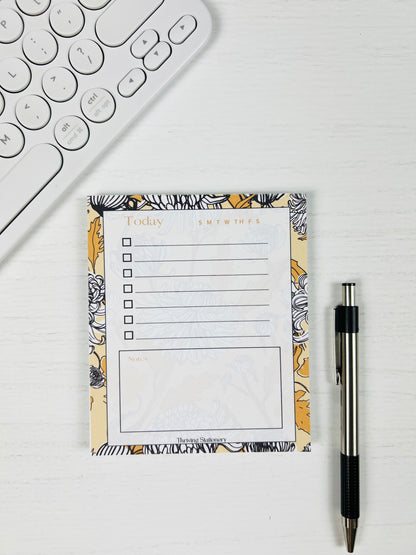 Black and Yellow Floral To-Do List Notepad with chrysanthemum floral design and daily checklist layout with a pen for scale
