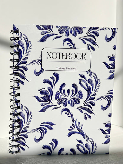Aesthetic blue and white spiral notebook with floral design, hardcover finish, and “Notebook” label by Thriving Stationery.