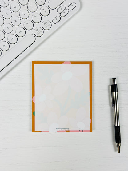 Notebook with floral border on a desk with a keyboard and pen