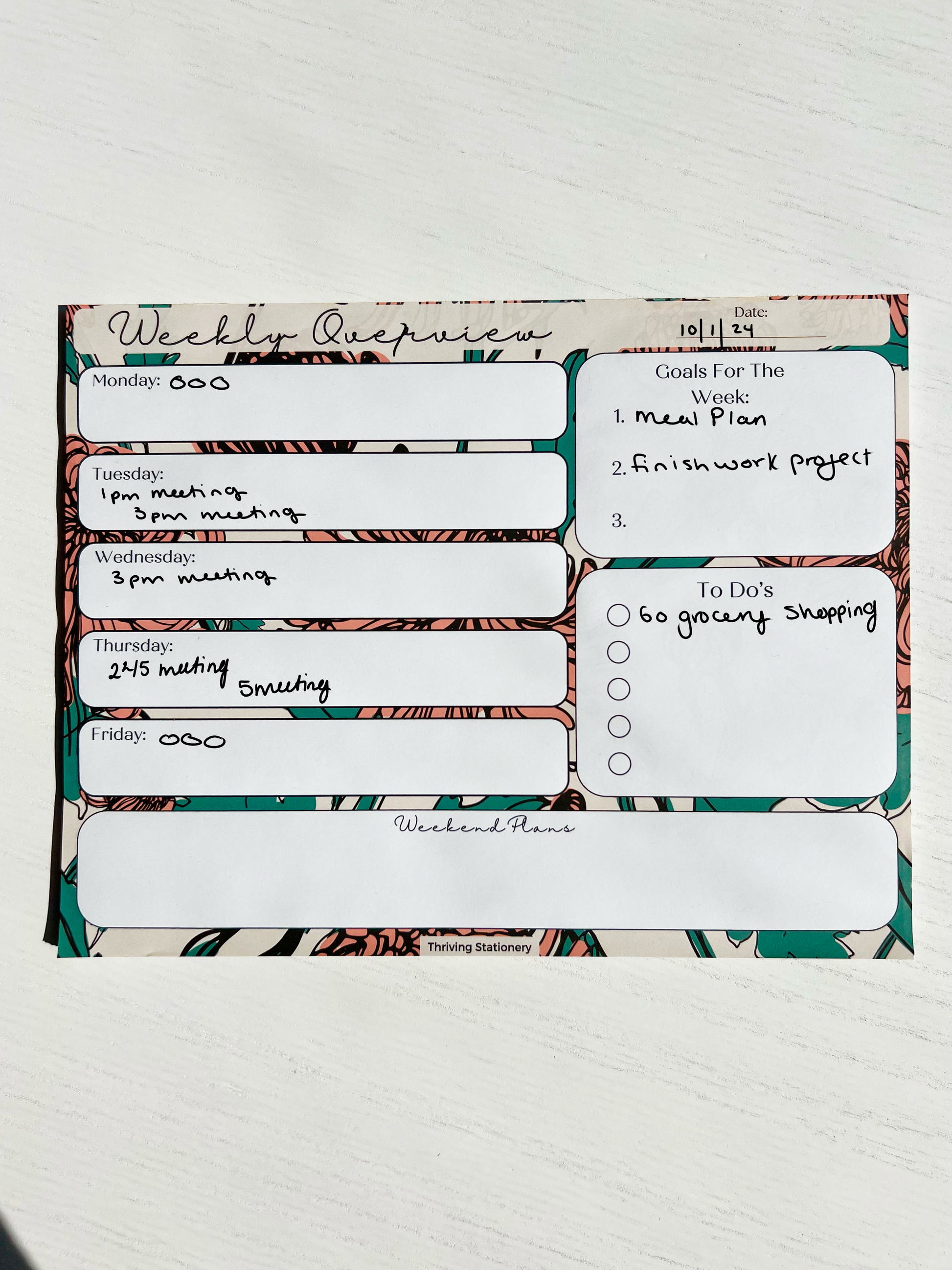 Weekly planner notepad with bold floral background featuring daily sections, weekly goals, to-do list with checkboxes, and weekend planning space.
