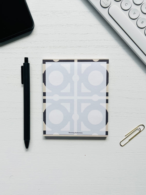Notebook with geometric design, pen, and paperclip on a white surface