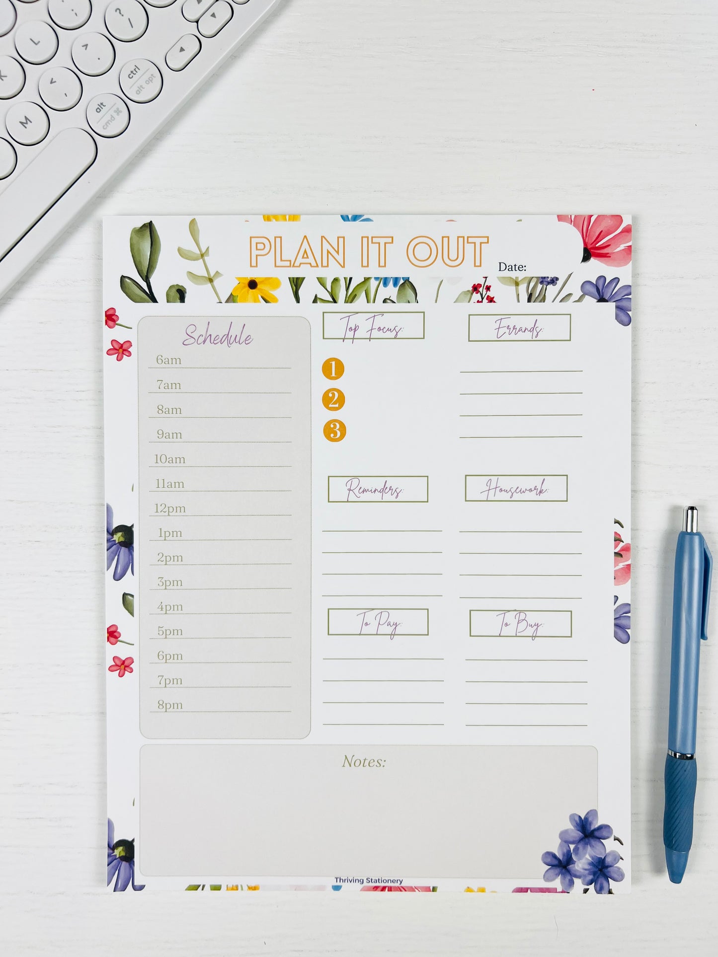 Floral-themed planner notepad with a pen on a white surface