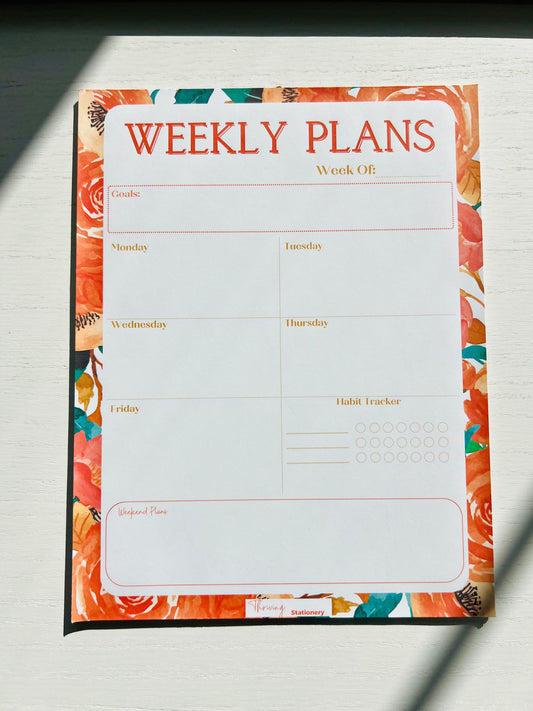 Weekly planner notepad with vibrant orange floral border featuring weekday layout, habit tracker, weekly goals section, and weekend planning space.