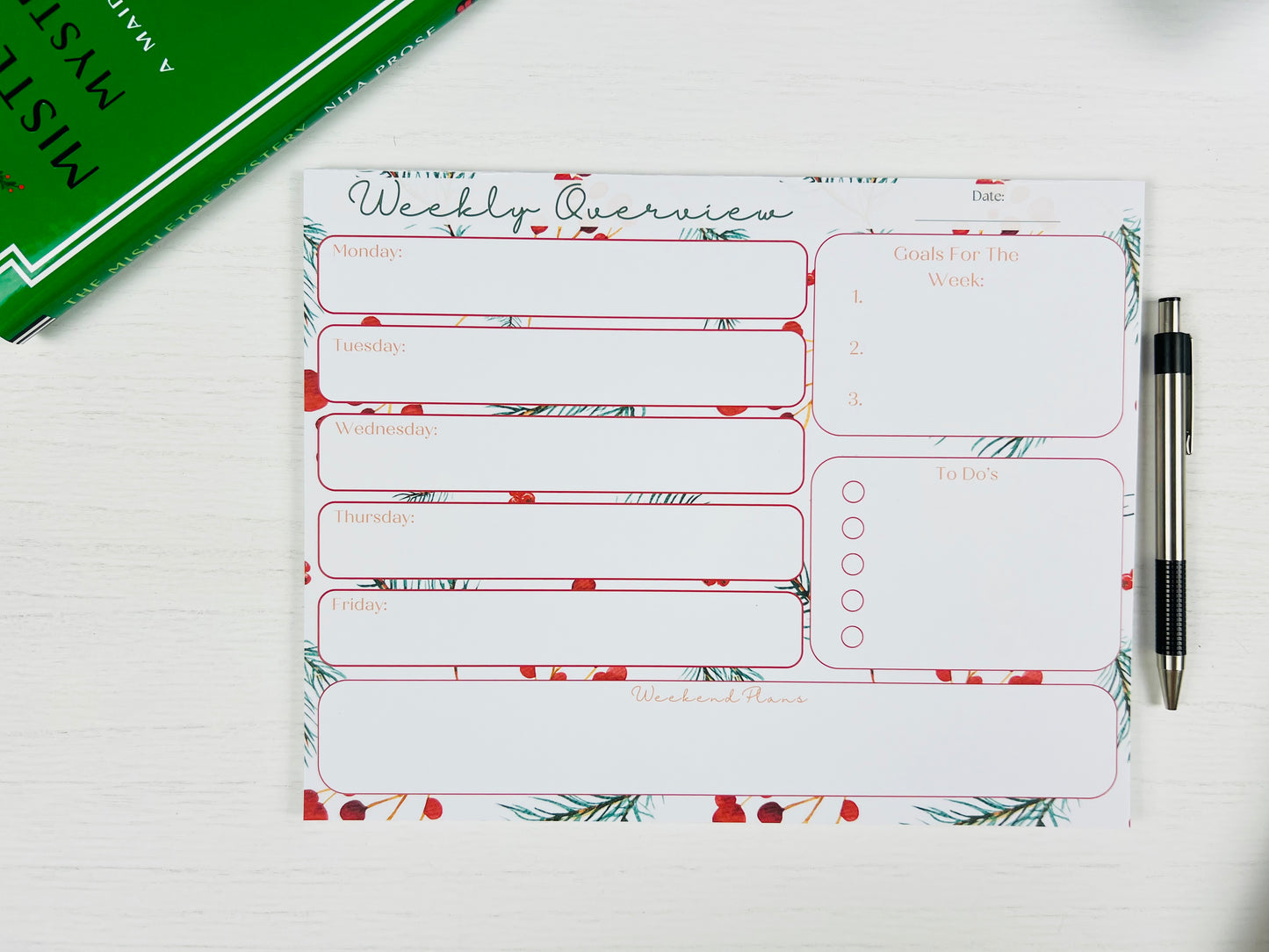 Weekly overview planner sheet with floral design on a white surface with a pen.