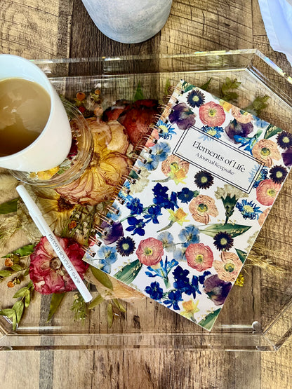 Floral notebook with a pen and mug on a wooden surface