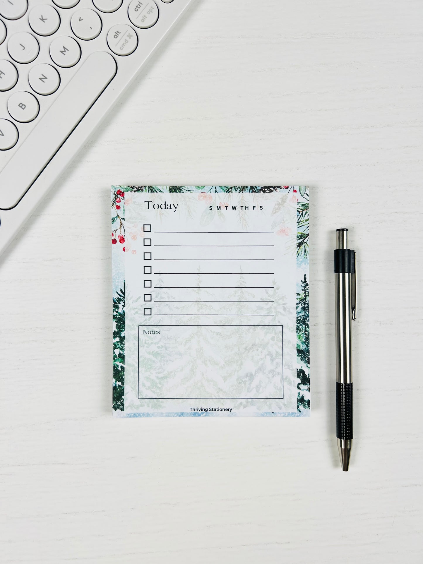 Notepad with a to-do list on a white surface next to a pen and keyboard.