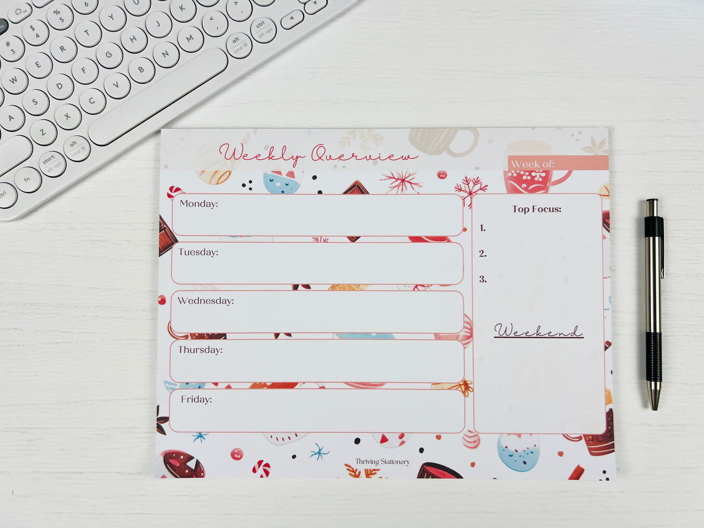 Weekly planner pad with colorful design on a white surface with a pen and keyboard.