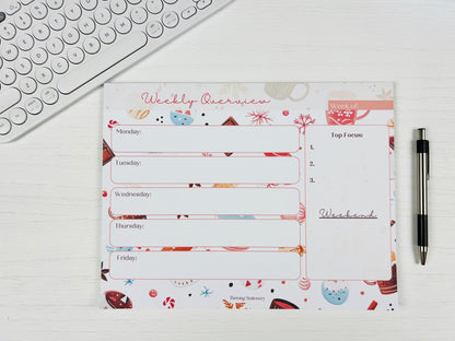 Weekly planner pad with colorful design on a white surface with a pen and keyboard.