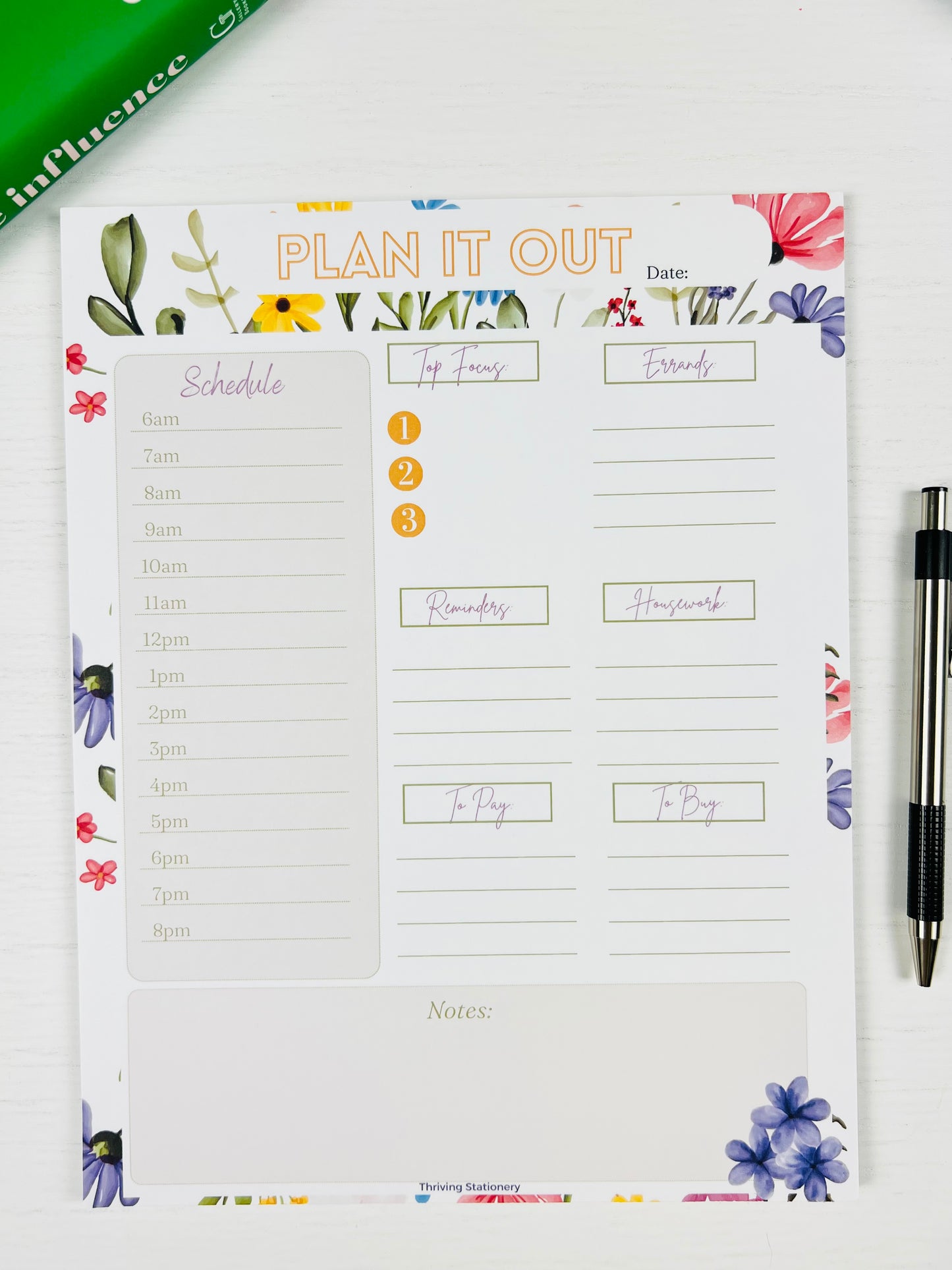 Letter sized floral planner notepad with a pen on a white surface