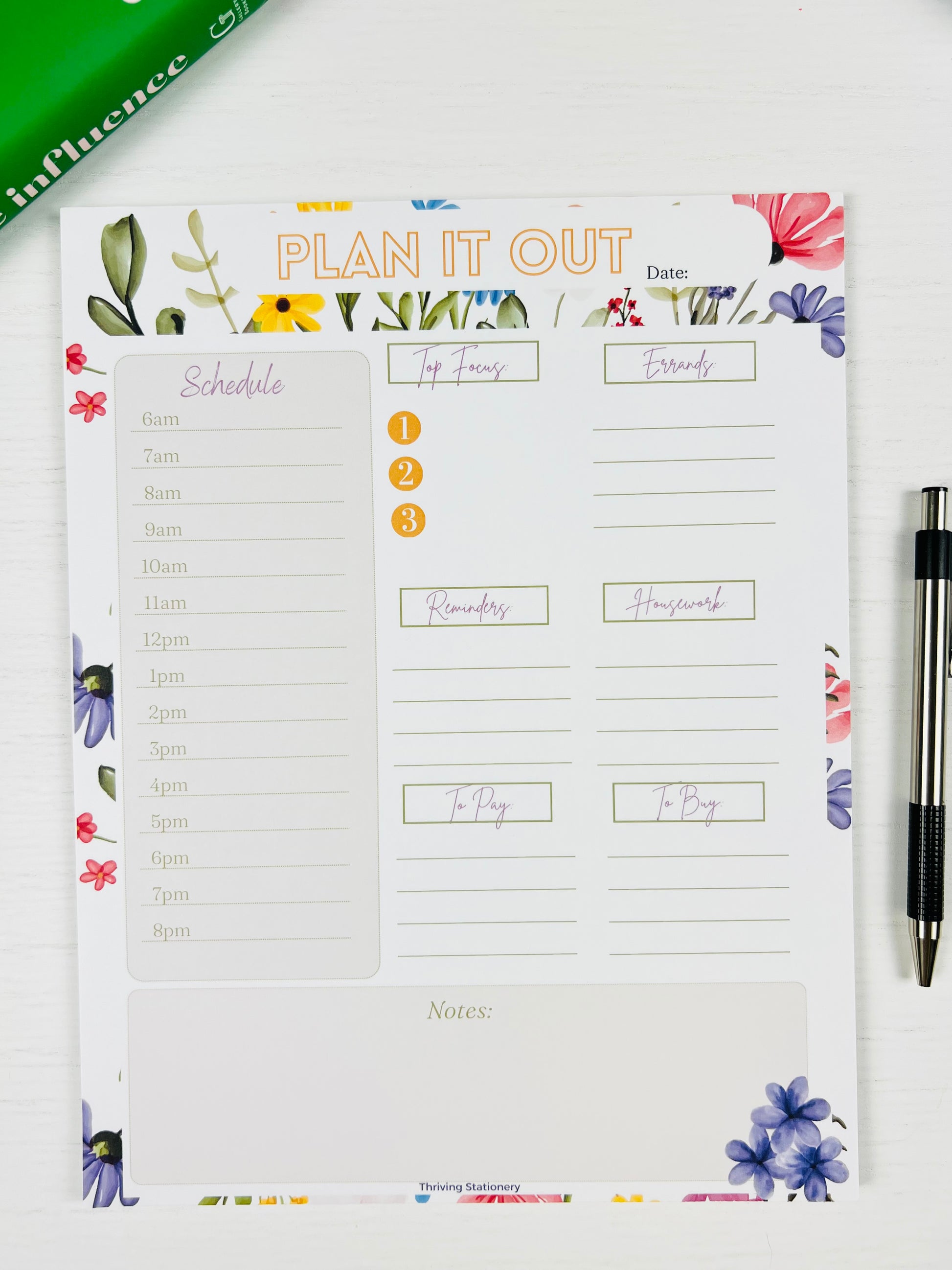 Letter sized floral planner notepad with a pen on a white surface