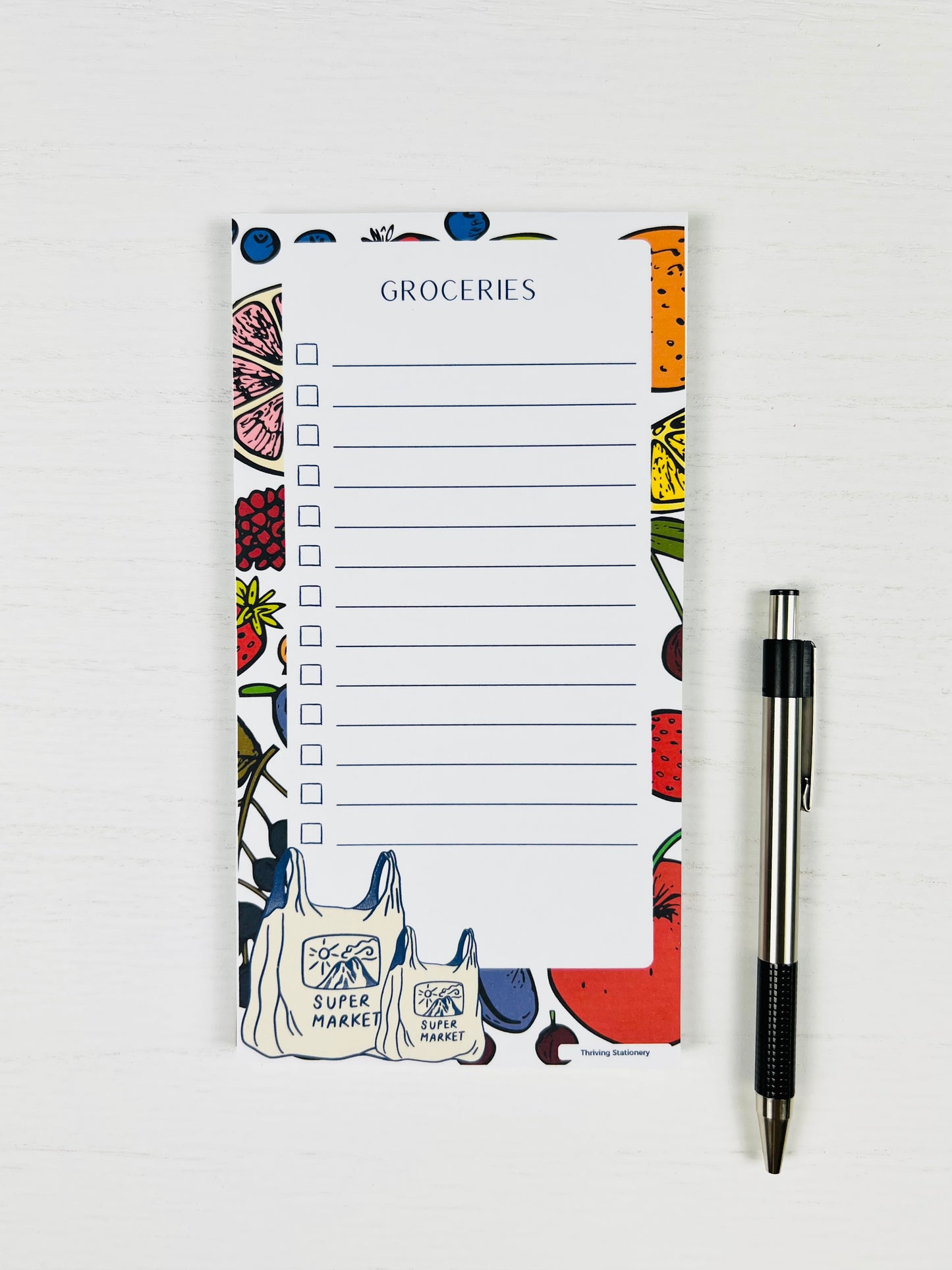 Super Market Magnetic Grocery List Notepad with fruit border and illustrated grocery bags with a pen for scale 