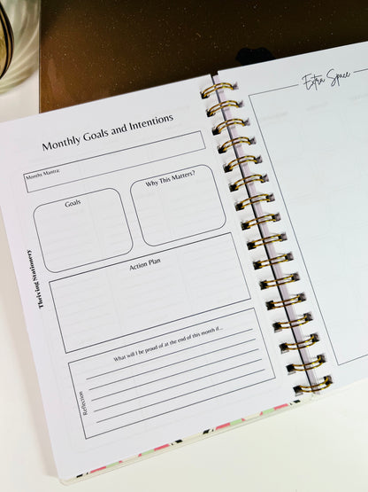 Spiral-bound planner with a page titled 'Monthly Goals and Intentions' on a white surface.