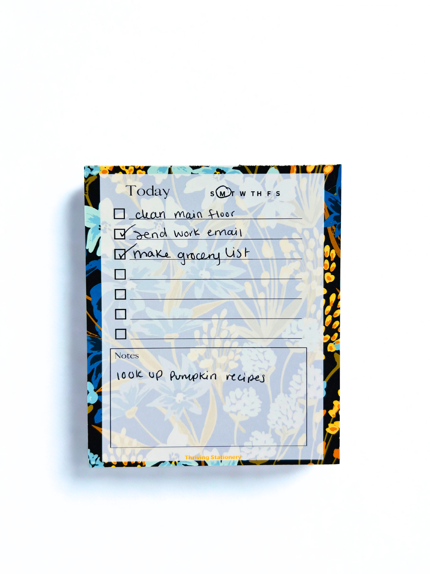 Navy Meadow Daily Planner Notepad with navy, blue, and gold floral border and daily checklist layout with sample writing