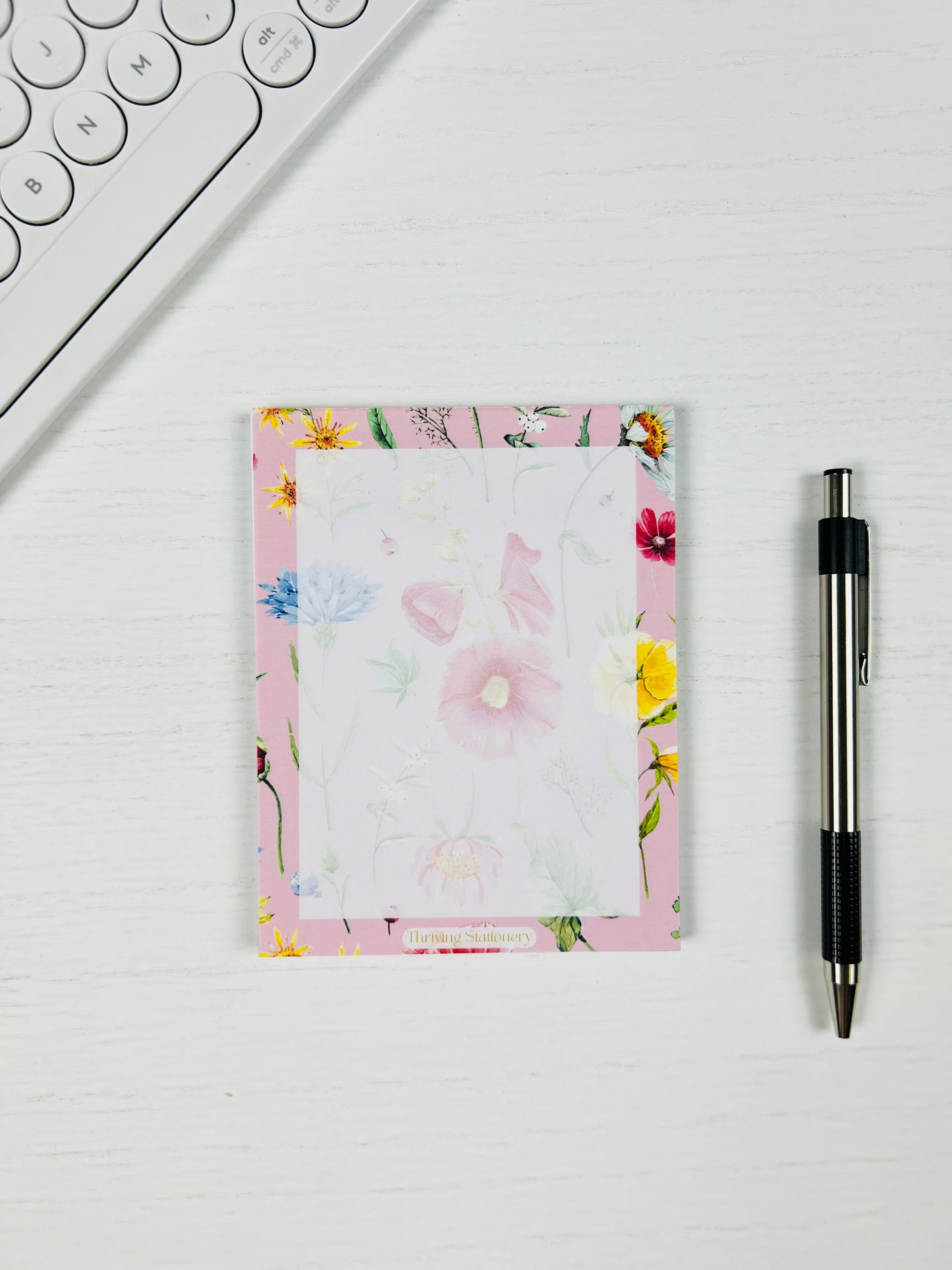Floral notepad with a pen on a white surface
