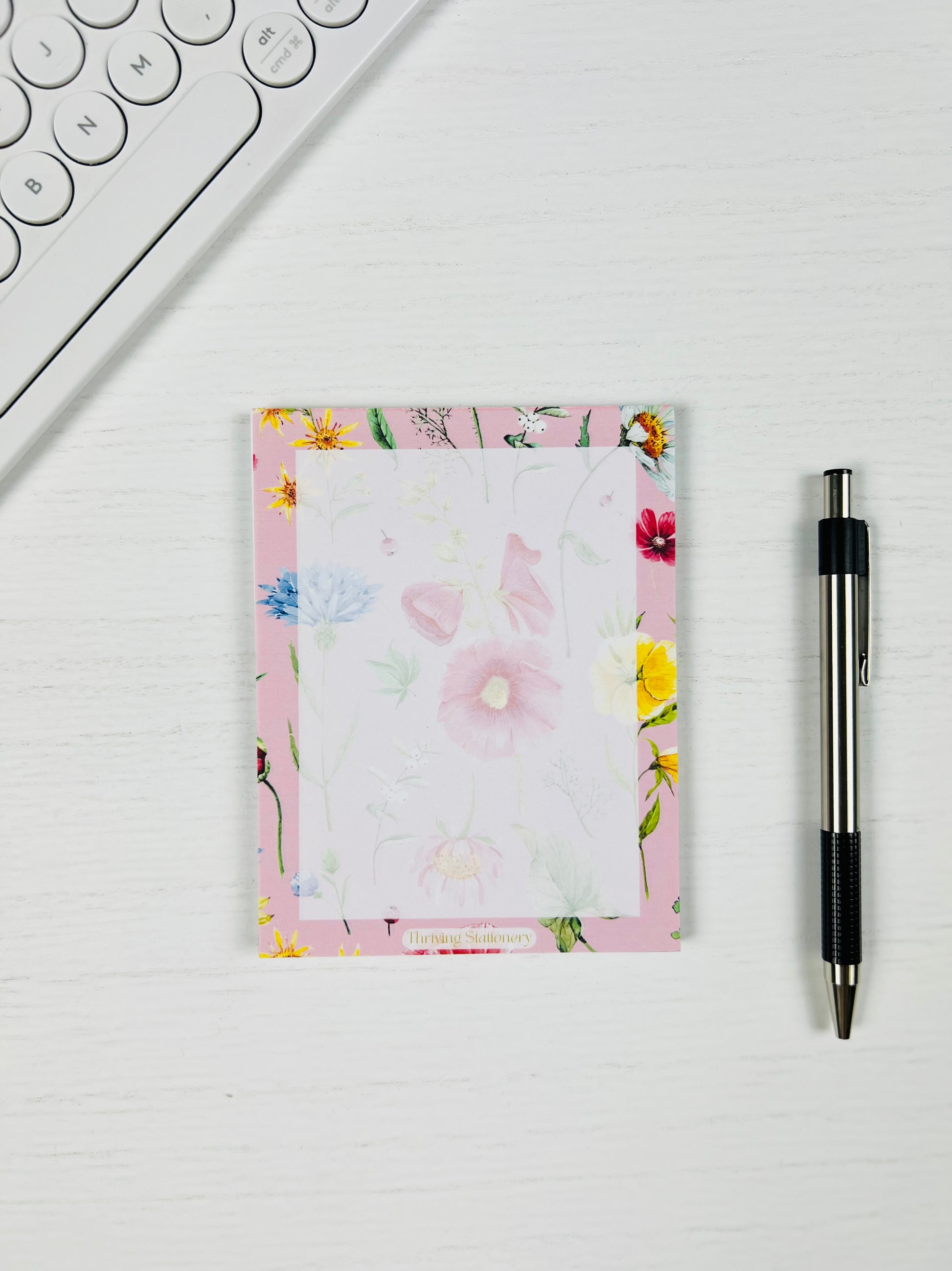 Floral notepad with a pen on a white surface