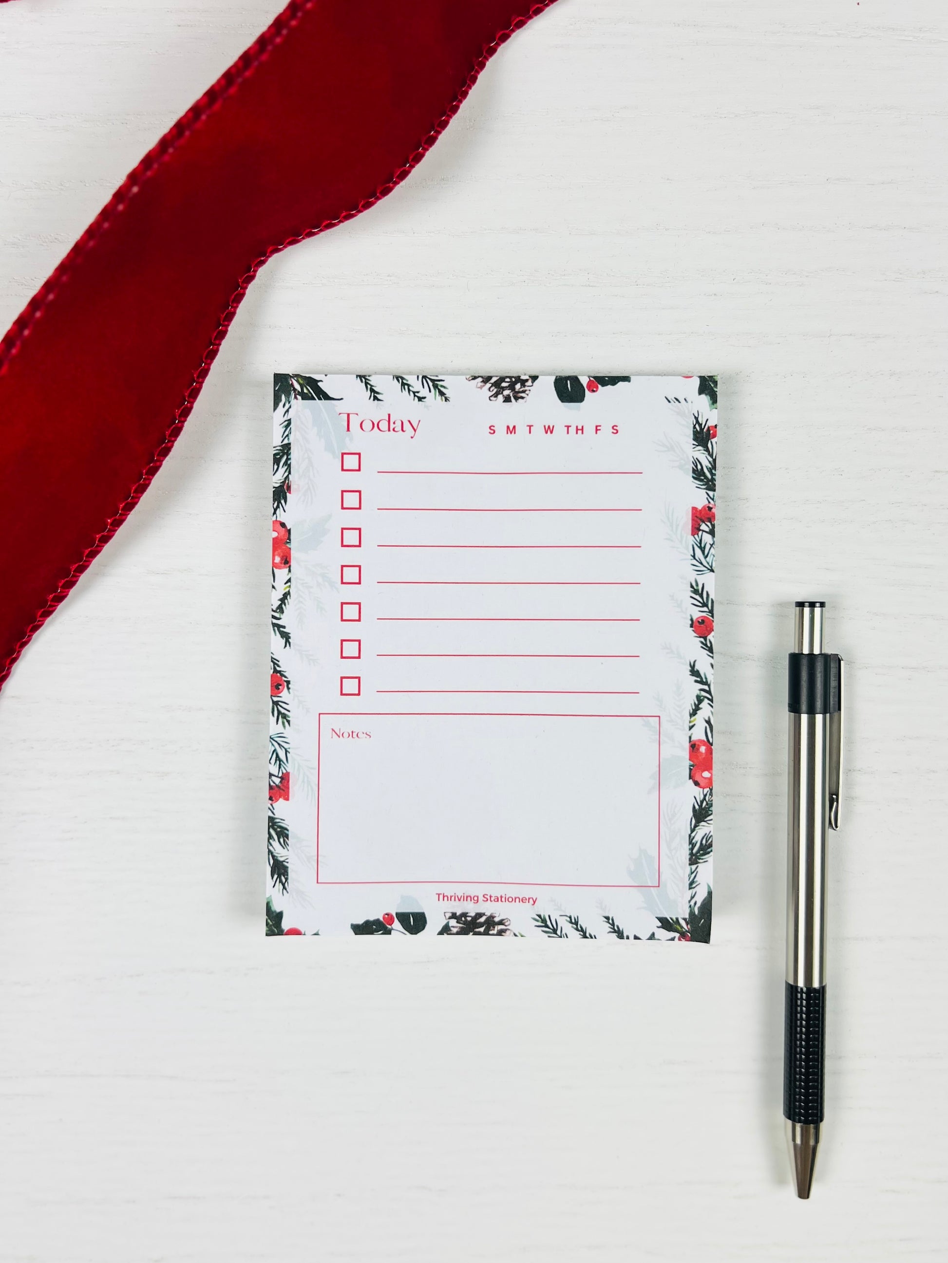 Floral-patterned notepad with a pen on a white background