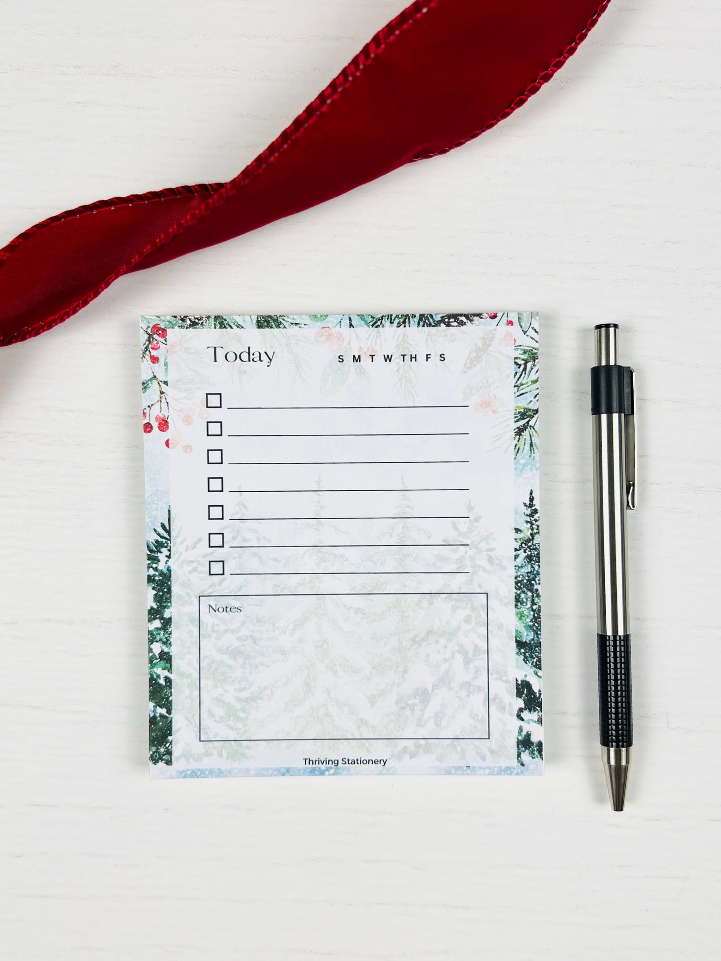Notepad with floral design and pen on a white background