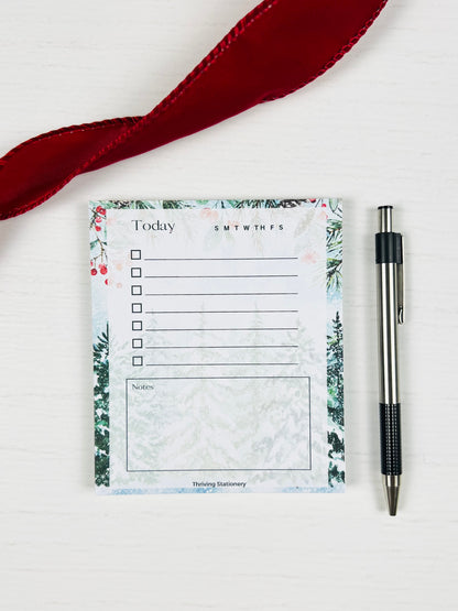 Notepad with floral design and pen on a white background