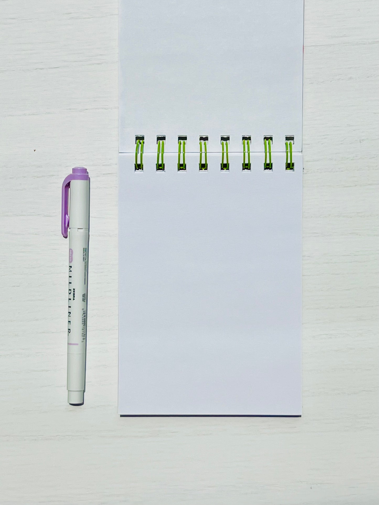 Floral Mini Notes Spiral Notepad with unlined pages alongside a pen for scale