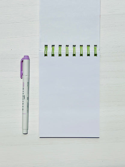 Floral Mini Notes Spiral Notepad with unlined pages alongside a pen for scale