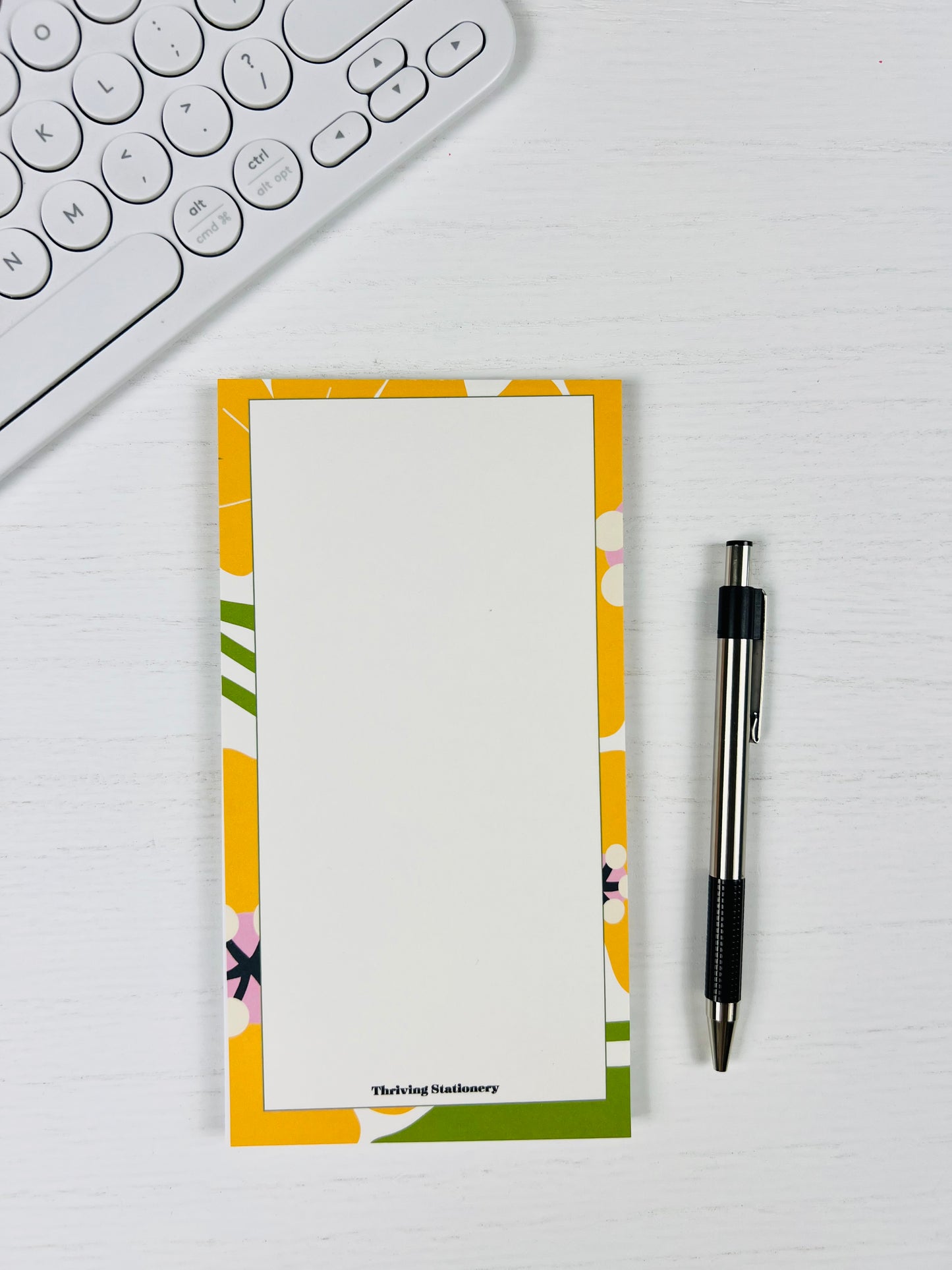 Floral notepad with a pen on a desk next to a keyboard