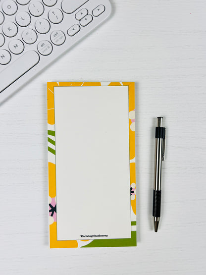 Floral notepad with a pen on a desk next to a keyboard