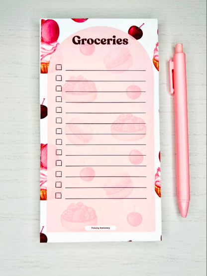 Sweet Treats Magnetic Grocery List Notepad with pink dessert illustrations and checkbox layout with a pen for scale