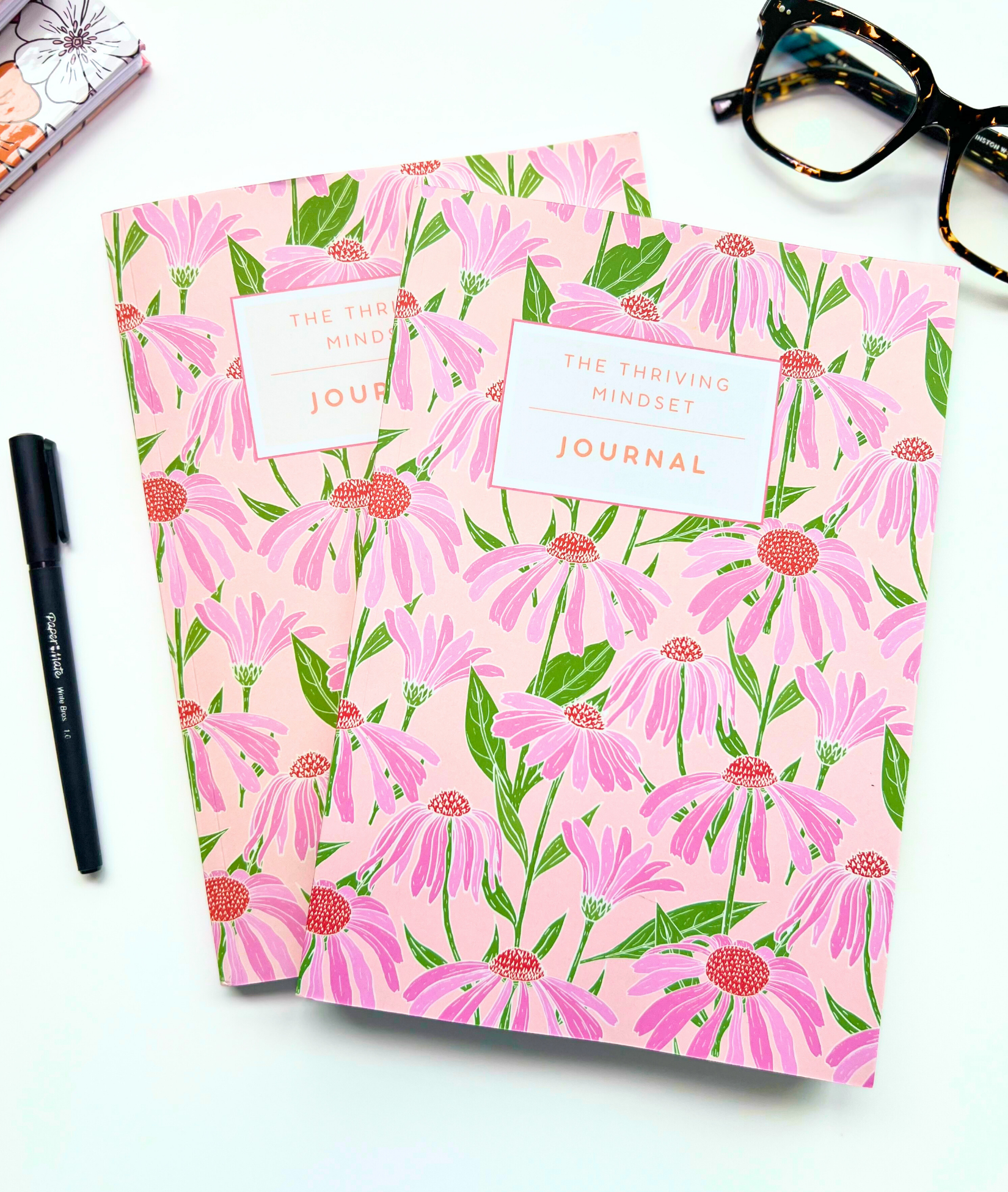 The Thriving Mindset Journal with pink floral cover and 90-day guided journaling layout