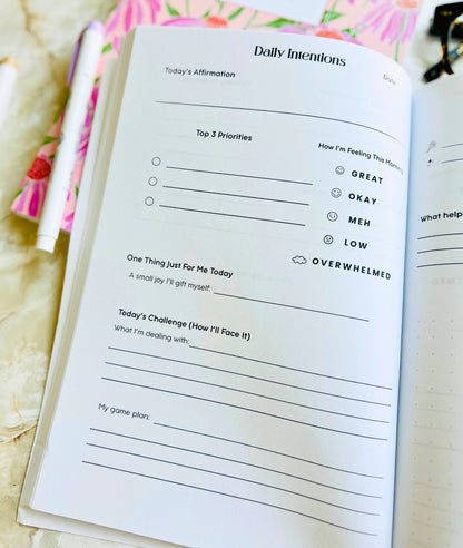 Open planner with daily intentions section on a floral background