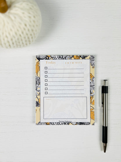 Floral-themed notepad with a pen on a white surface